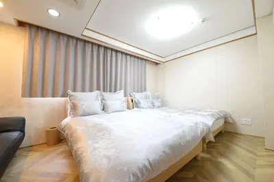 a large white bed in a room with a couch at la3 hotel \u65b0\u5bbf\u4e09\u968e\u5efa\u3066\u4e00\u8ed2\u5bb6\uff08\u5c4b\u5185\u30a8\u30ec\u30d9\u30fc\u30bf\u30fc\u4ed8\u304d) in Tokyo