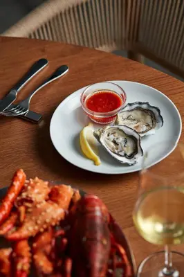a plate of oysters and sauce on a table at TRUNK(HOTEL) YOYOGI PARK in Tokyo