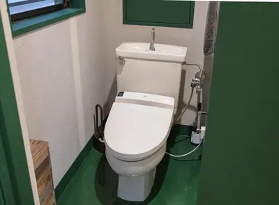 a white toilet in a bathroom with a green floor at \u30b5\u30f3\u30e2\u30fc\u30eb\u7b2c\u4e09\u30de\u30f3\u30b7\u30e7\u30f3 in Tokyo