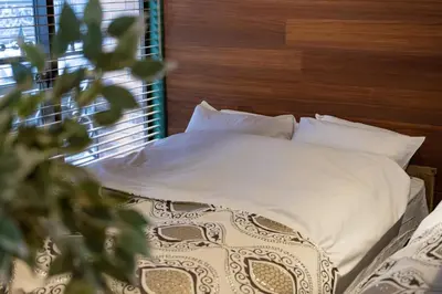a bed with white pillows and a wooden head board at \u30b5\u30f3\u30e2\u30fc\u30eb\u7b2c\u4e09\u30de\u30f3\u30b7\u30e7\u30f3 in Tokyo