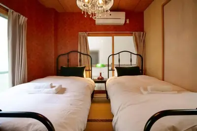two beds in a room with red walls and a chandelier at 1F Facing Skdytree 6min stn Direct NRT&HND&Disney in Tokyo