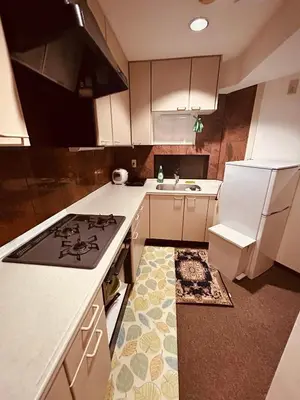 a kitchen with a stove and a white refrigerator at \u6c60\u888b\u4e09\u99c5\u306e\u5bb6 \u5927\u5c71\u99c5\u304b\u3089\u5f92\u6b694\u5206 in Tokyo