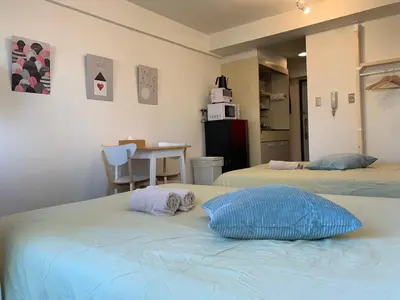 a room with two beds and a kitchen with a table at Studio in the center of Shibuya \u6e0b\u8c37\u9053\u7384\u5742 in Tokyo