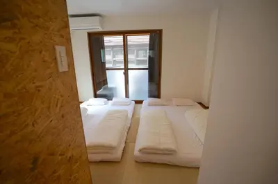 a room with three beds and a window at da Haus Ikebukuro in Tokyo