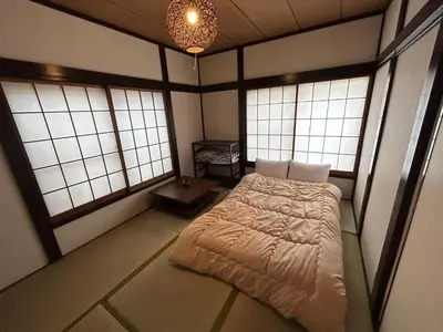 a bedroom with a bed in a room with windows at 1970's Japanese style dorm house in Tokyo