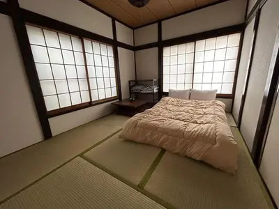 a bedroom with a bed in a room with windows at 1970's Japanese style dorm house in Tokyo