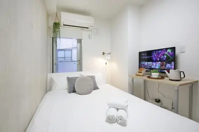 a bedroom with a white bed and a desk at Real Kinshi 201 in Tokyo