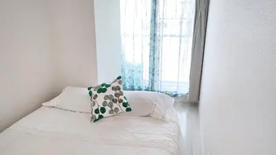 a bed with a pillow on it next to a window at Ookubo! Shinjuku! kabukicho! \u65b0\u5bbf\u4e2d\u5fc3! \u5927\u4e45\u4fdd! \u65b0\u5bbf\u6b4c\u821e\u4f0e! \u5730\u94c1\u7ad9\u6b65\u884c3\u5206! Autolock! \u667a\u80fd\u9a6c\u6876! \u9ad8\u901f\u65e0\u9650\u5236\u7f51\u8def!601 in Tokyo
