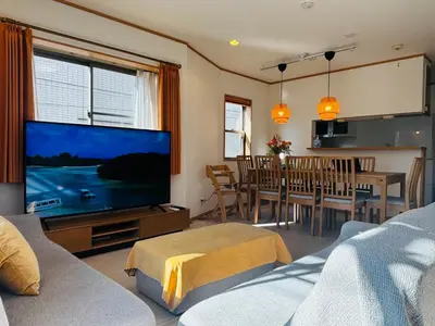 a living room with a large television and a dining room at Kamei House in Tokyo