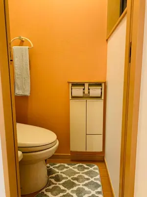 an orange bathroom with a toilet and a rug at Kamei House in Tokyo