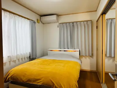 a small bedroom with a yellow bed in front of a window at Kamei House in Tokyo