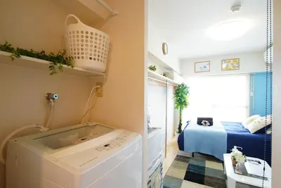 a laundry room with a washing machine and a bed at Kameari 1108 Budget Stay High Floor Near Station Mall Disney Access in Tokyo