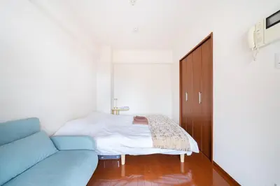 a bedroom with a bed and a blue couch at \u30ac\u30a4\u30a2\u6b4c\u821e\u4f0e\u753a\u58f1\u756a\u9928602 in Tokyo