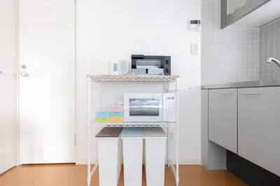a small white kitchen with a microwave on a shelf at Granduo \u677e\u6fe4 in Tokyo