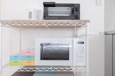 a microwave oven sitting on a shelf with books at Granduo \u677e\u6fe4 in Tokyo