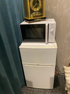a microwave on top of a dresser with a clock on top at 54Journey Roppongi in Tokyo