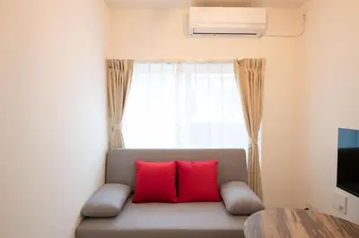 a couch with two red pillows in front of a window at \u58a8\u7530Dias in Tokyo