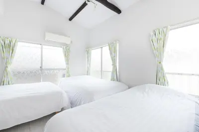 two beds in a white room with windows at Sola Stay Kanegafuchi in Tokyo