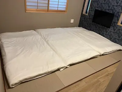 a bed with white sheets on it in a room at Asagaya House by Tranova in Tokyo