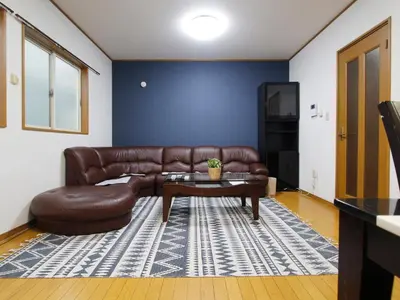 a living room with a brown leather couch and a table at NEW_OPEN\u65b0\u5bbf\u30a8\u30ea\u30a2\u30fb\u5bb6\u65cf\u3084\u30b0\u30eb\u30fc\u30d7\u6700\u9069\u30fb\u5e0c\u5c11\u72ec\u7acbTOWNHOUSE\u3000 in Tokyo