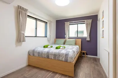 a bedroom with a bed with purple walls and windows at Ici Japon Village in Tokyo