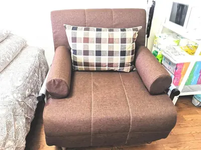 a brown chair with a pillow next to a bed at DP House in Tokyo