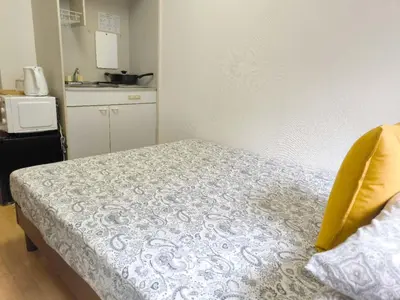 a small bedroom with a bed and a kitchen at DP House in Tokyo