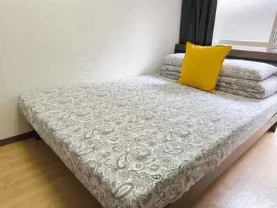 a bed with a yellow pillow on top of it at DP House in Tokyo