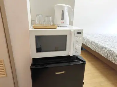 a microwave sitting on top of a black refrigerator at DP House in Tokyo