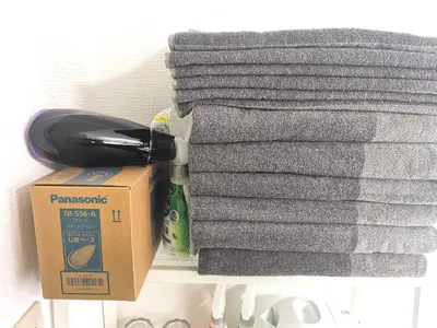 a pile of towels and a box on a shelf at DP House in Tokyo