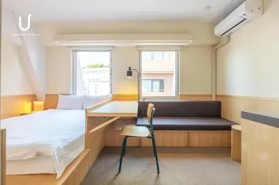 a bedroom with a bed and a desk and a bed and a chair at Hotel Residence Ohashi Kaikan Tokyo Shibuya in Tokyo