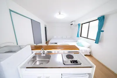 a kitchen with a sink in a room with two beds at SUA HOTEL Nishikasai in Tokyo