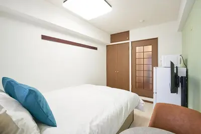 a bedroom with a white bed and a refrigerator at \u30ac\u30fc\u30c7\u30f3\u5927\u585a in Tokyo