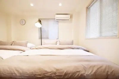 a bedroom with two beds and a window with a clock at TERRACE HOUSE Shibuya Maruyamacho - Vacation STAY 79338v in Tokyo