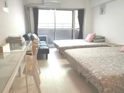 a room with two beds and a desk and a window at Lions Mansion Kabukicho No2 with2 bedroom in Tokyo