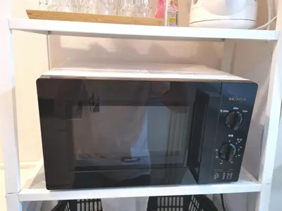 a black microwave on a shelf in a kitchen at Lions Mansion Kabukicho No2 with2 bedroom in Tokyo