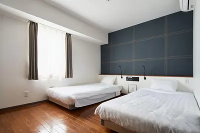 a bedroom with two beds and a blue wall at TOKIO's HOTEL in Tokyo