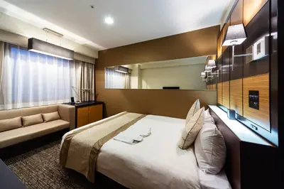 a hotel room with a large bed and a couch at KOKO HOTEL Shinjuku Yotsuya- formerly Hotel Wing International Premium Tokyo Yotsuya in Tokyo