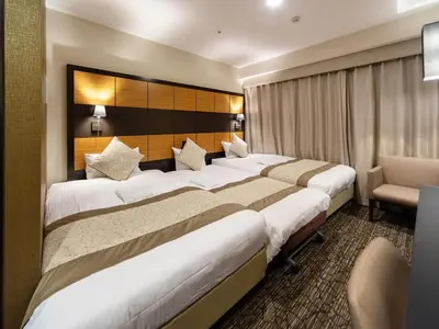 a row of beds in a hotel room at KOKO HOTEL Shinjuku Yotsuya- formerly Hotel Wing International Premium Tokyo Yotsuya in Tokyo