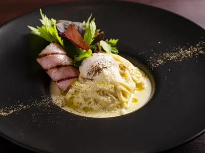 a black plate of food with pasta and meat at KOKO HOTEL Shinjuku Yotsuya- formerly Hotel Wing International Premium Tokyo Yotsuya in Tokyo
