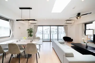 a living room with a white couch and a table and chairs at Generous Forest 301 in Tokyo