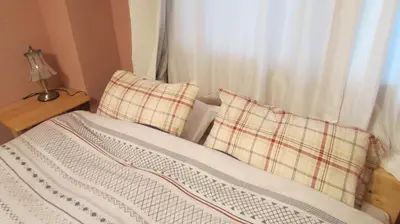 a bed with two plaid pillows sitting next to a window at Cheese Cozy Condo in Tokyo