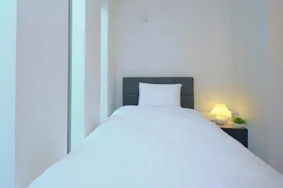 a white bed with a white pillow and a lamp at ACOE HATSUDAI - 4BR Entire Home Upscale Area in Tokyo