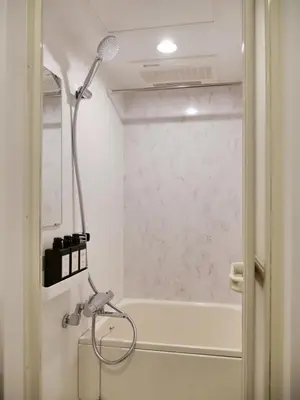 a shower in a bathroom next to a bath tub at Okubo Shinjuku new open Capsule hotel in Tokyo
