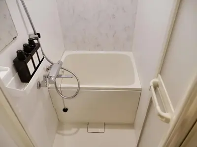 a small white bathroom with a light on the wall at Okubo Shinjuku new open Capsule hotel in Tokyo