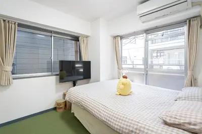 a teddy bear sitting on a bed in a bedroom at Two-bedroom, 6-minute walk to the Yamanote Line in Tokyo