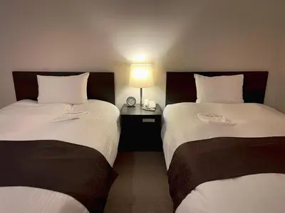 two beds in a hotel room with a lamp between them at Shinjuku Sun Park Hotel in Tokyo