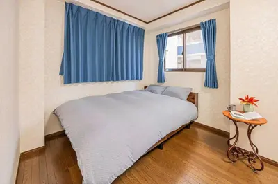 a bedroom with a large bed with blue curtains at \u53f0\u6771\u533a\u5e83\u3005\u5439\u304d\u629c\u3051\u30ea\u30d3\u30f3\u30b0\u306e\u30e1\u30be\u30cd\u30c3\u30c8\u30bf\u30a4\u30d7\u306e\u304a\u5bb6 in Tokyo