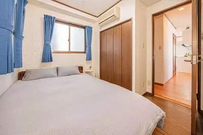 a bedroom with a large bed with blue curtains at \u53f0\u6771\u533a\u5e83\u3005\u5439\u304d\u629c\u3051\u30ea\u30d3\u30f3\u30b0\u306e\u30e1\u30be\u30cd\u30c3\u30c8\u30bf\u30a4\u30d7\u306e\u304a\u5bb6 in Tokyo