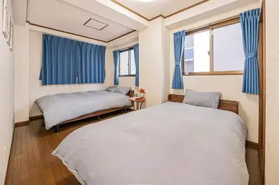 a bedroom with two beds and blue curtains at \u53f0\u6771\u533a\u5e83\u3005\u5439\u304d\u629c\u3051\u30ea\u30d3\u30f3\u30b0\u306e\u30e1\u30be\u30cd\u30c3\u30c8\u30bf\u30a4\u30d7\u306e\u304a\u5bb6 in Tokyo